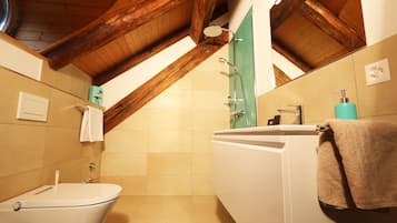 A bathroom with a white toilet, a sink with a mirror, and a shower.