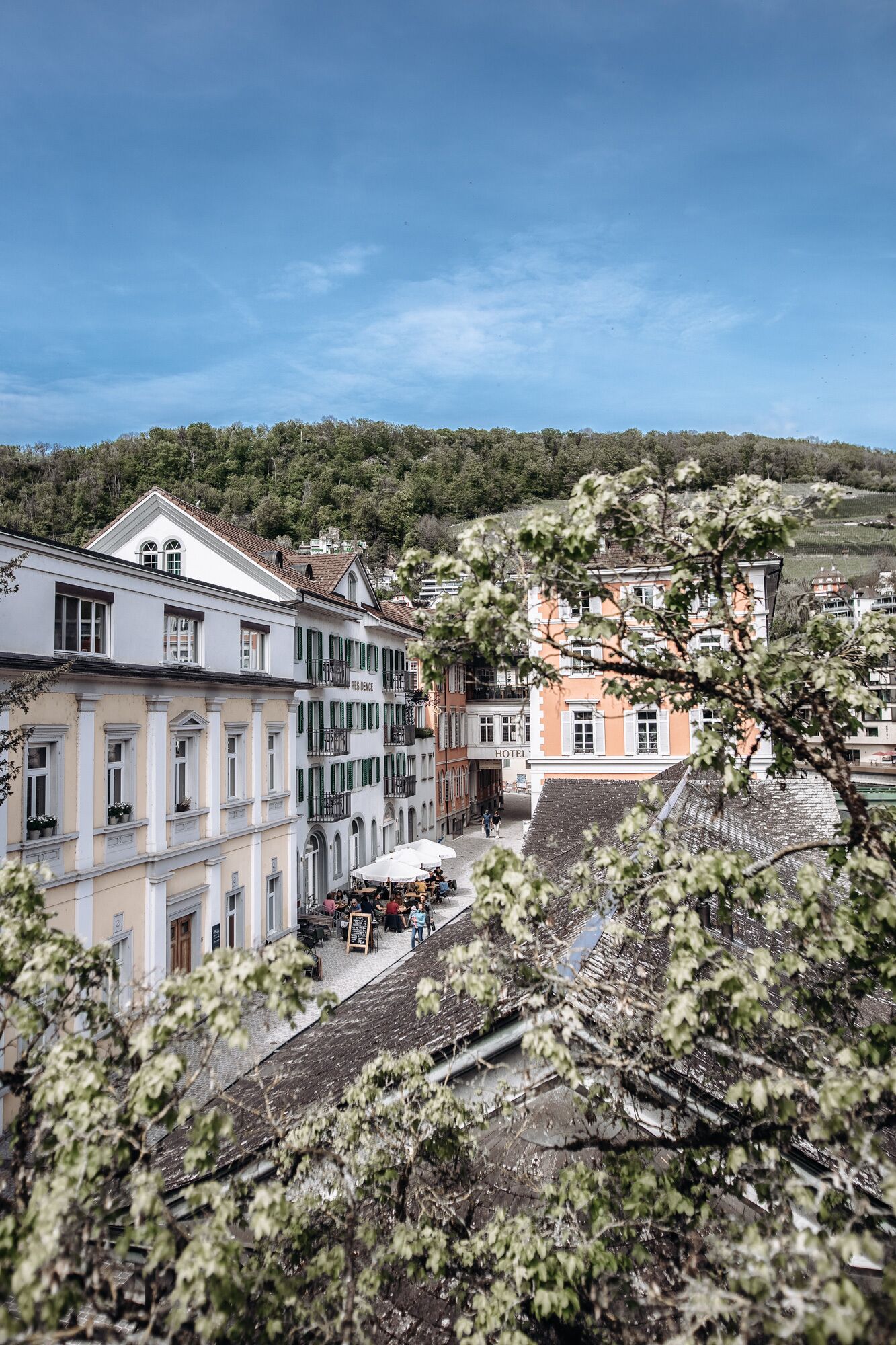 Un hotel con un patio interior, rodeado de edificios con balcones y vistas a un paisaje montañoso.