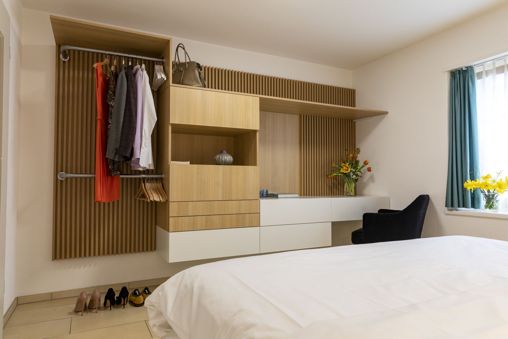 A modern bedroom with a built-in wardrobe, a bedside table, and a window with curtains.