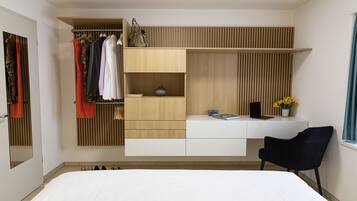 A modern bedroom with a bed, a built-in wardrobe, a desk with a chair, and a window with curtains.