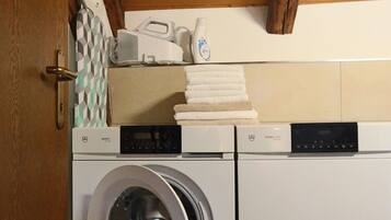 A laundry room with a washing machine and dryer, wooden ceiling, and a tiled floor.