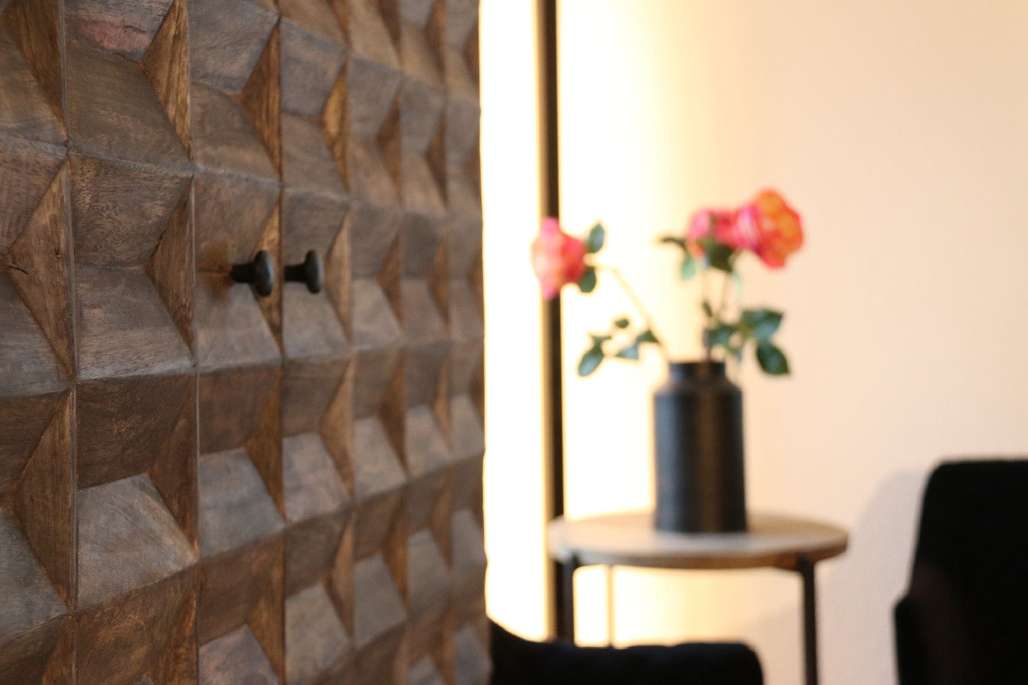 A wall with a geometric pattern and a vase with flowers on a table.