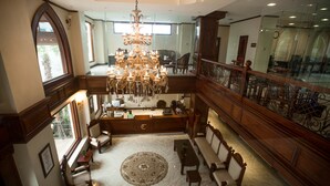 Un vestíbulo imponente con un gran candelabro, muebles de madera y un piso de mármol.