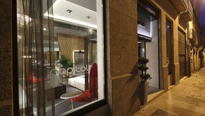 A hotel interior with a modern design, featuring a seating area with a red chair and a small table, and a potted plant. - Capitol Boutique Hotel (Santiago de Compostela)