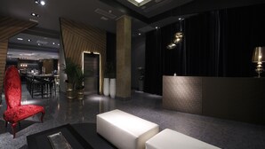 A modern lobby with a red upholstered chair, white seating, and a reception desk. - Capitol Boutique Hotel (Santiago de Compostela)