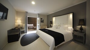 A modern hotel room with a large bed, bedside tables, a desk, and a seating area with a sofa and coffee table. - Capitol Boutique Hotel (Santiago de Compostela)