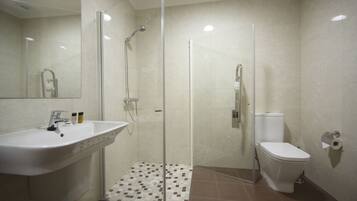 Un baño moderno con ducha de vidrio, lavamanos blanco y un inodoro.