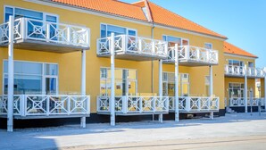 A yellow building with multiple balconies and a red roof. - Plesners Havnelejligheder (Skagen)