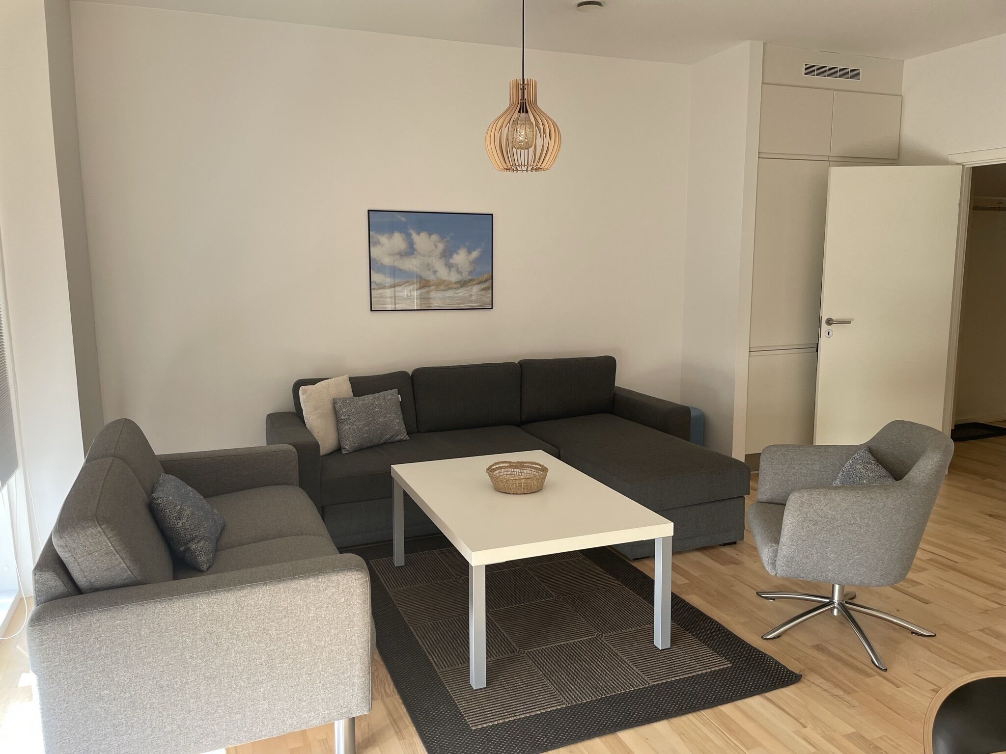 A modern living room with a grey sectional sofa, a white coffee table, and a grey armchair.