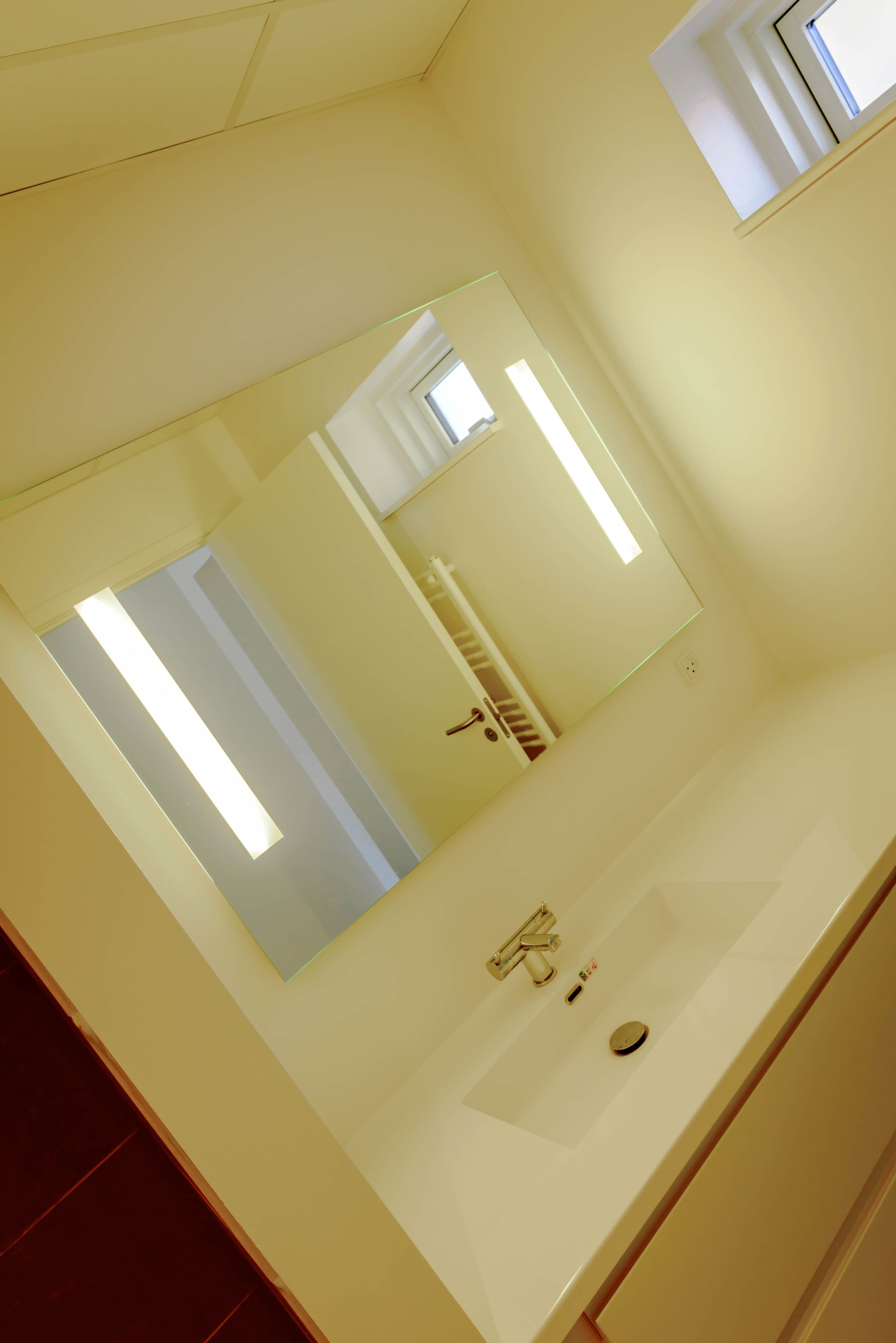 Een badkamer met een grote spiegel, een wastafel en een handdoekhouder.