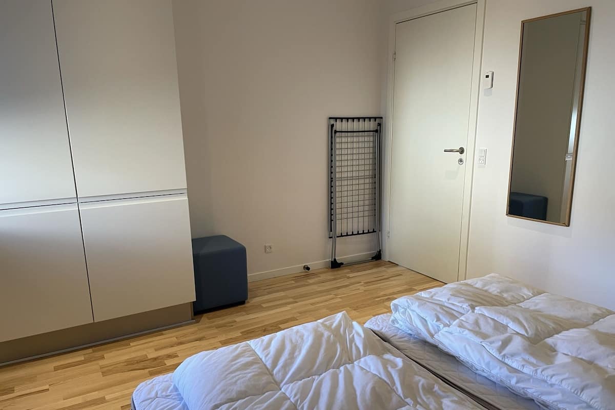 A bedroom with a bed, a wardrobe, a radiator, and a mirror.