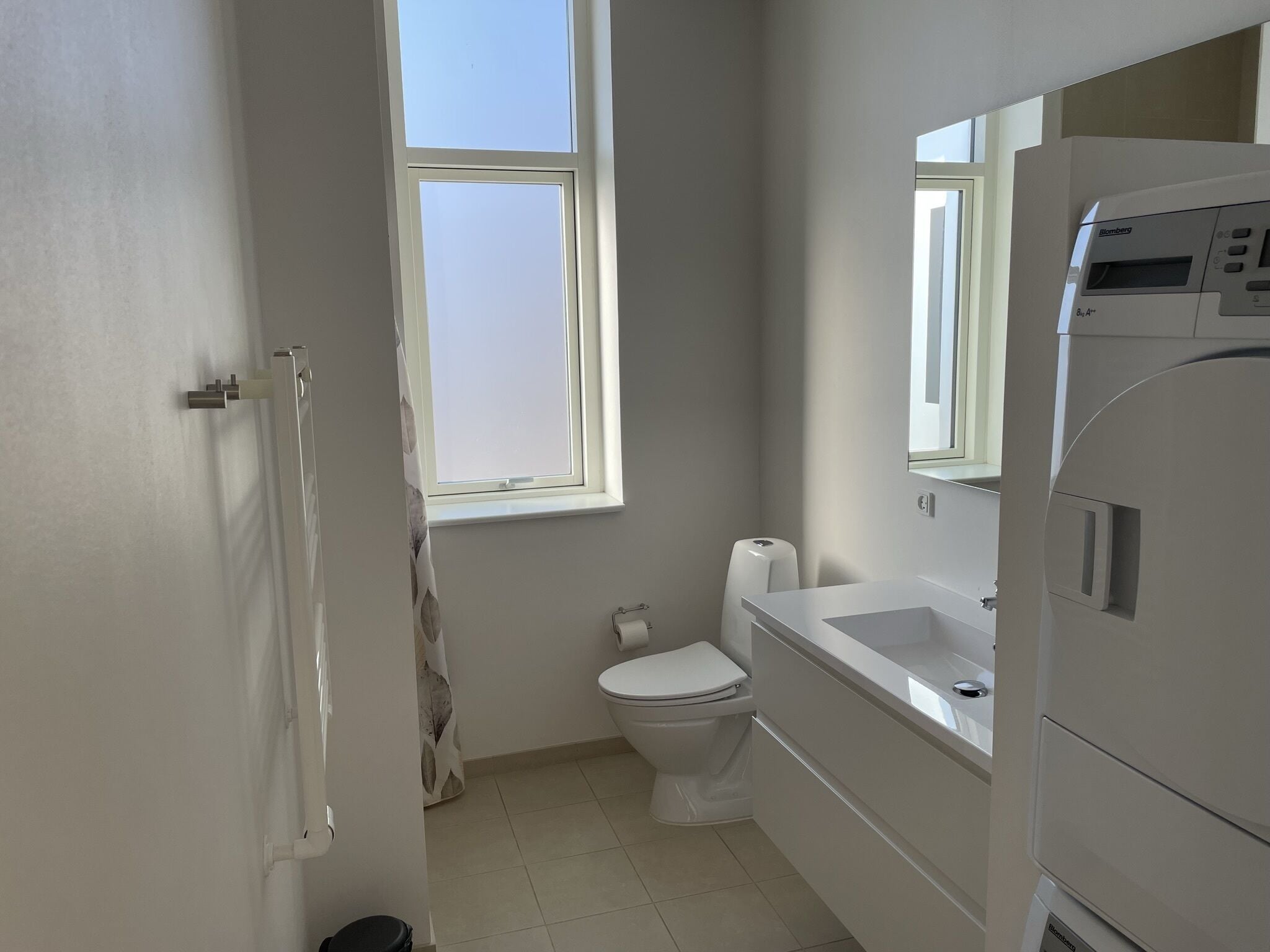 Un baño pequeño y moderno con inodoro, lavamanos y ventana.