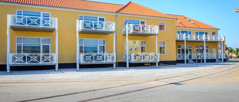 Un bâtiment jaune avec des balcons et un toit rouge.
