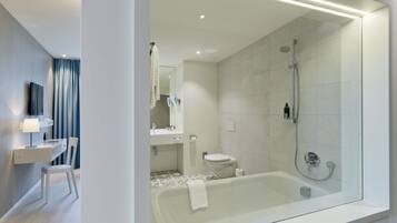 Un baño moderno con ducha de vidrio, bañera y tocador con espejo.