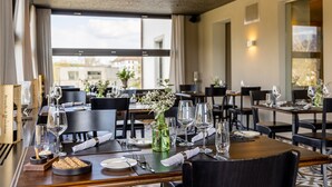Een restaurant met gedekte tafels, met helder glaswerk, borden en een groene fles.