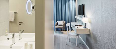 A modern bathroom with a large mirror, sink, and towel rack. The room has a wooden floor and a blue curtain.