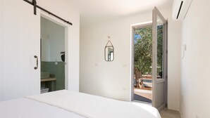 Ein Schlafzimmer mit einem Bett, einer Schiebetür, die auf einen Balkon führt, und einem kleinen Spiegel an der Wand.