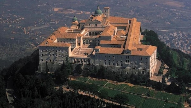 A large, historic building with multiple domes and a prominent central tower, surrounded by lush greenery and a hilly landscape. - Hotel Ristorante La Campagnola (Cassino)