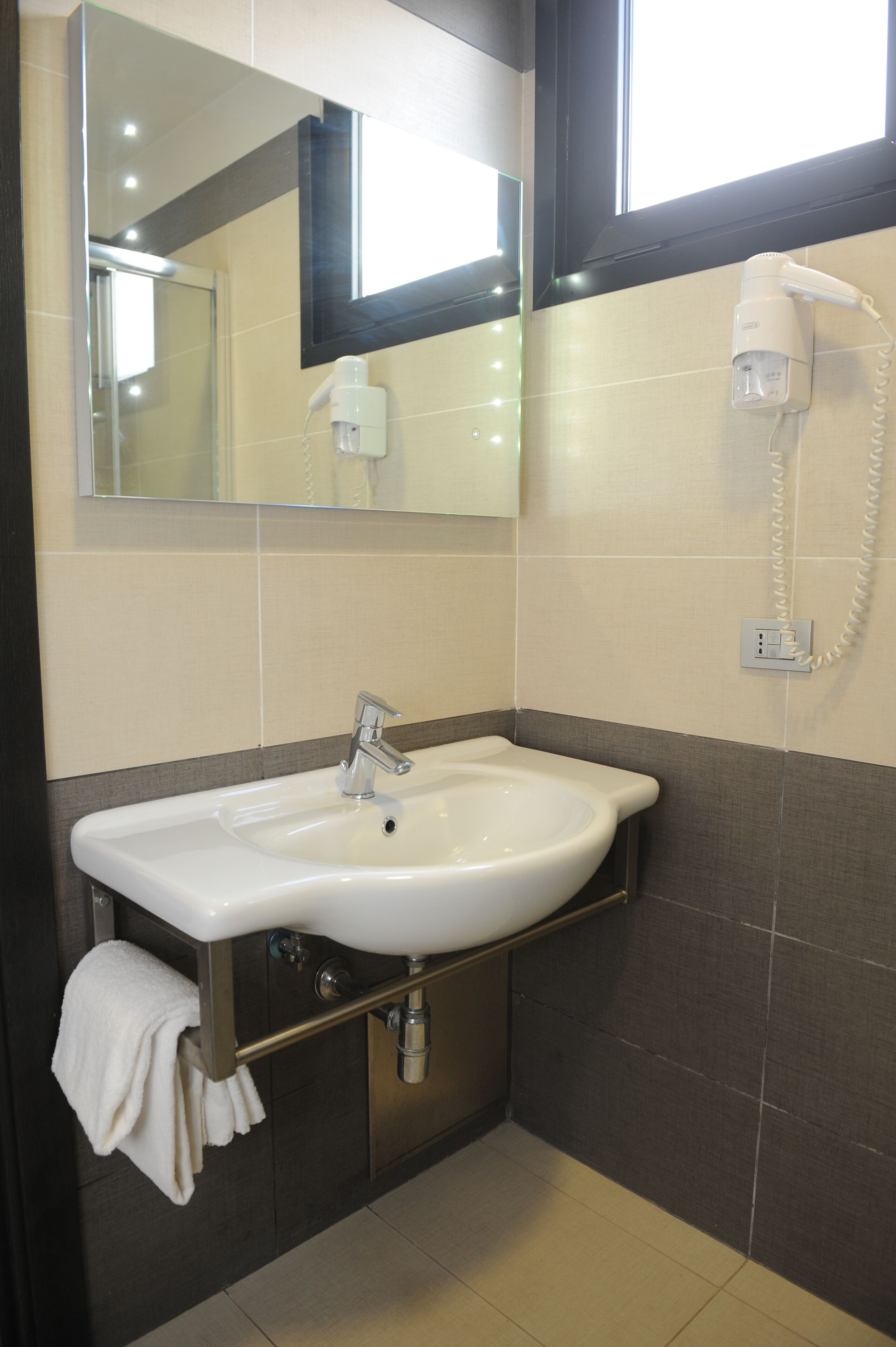 A bathroom with a white sink, a mirror, a hairdryer, and a towel rack.