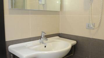 A bathroom with a white sink, a mirror, a hairdryer, and a towel rack.