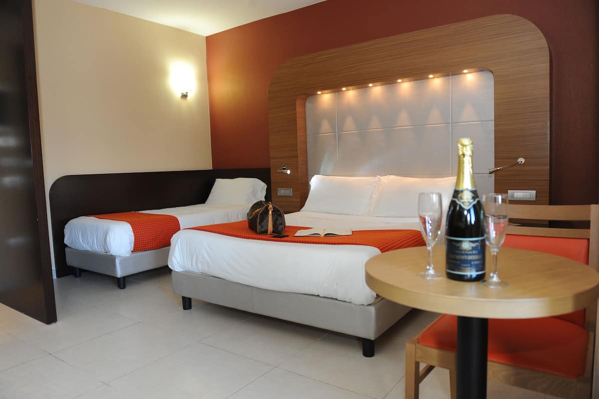 Ett hotellrum med två sängar, en sänggavel i trä, ett bord med en flaska champagne och två glas.