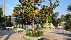 An outdoor dining area with tables and chairs, surrounded by a garden with a variety of plants and flowers. - Hotel Ristorante La Campagnola (Cassino)