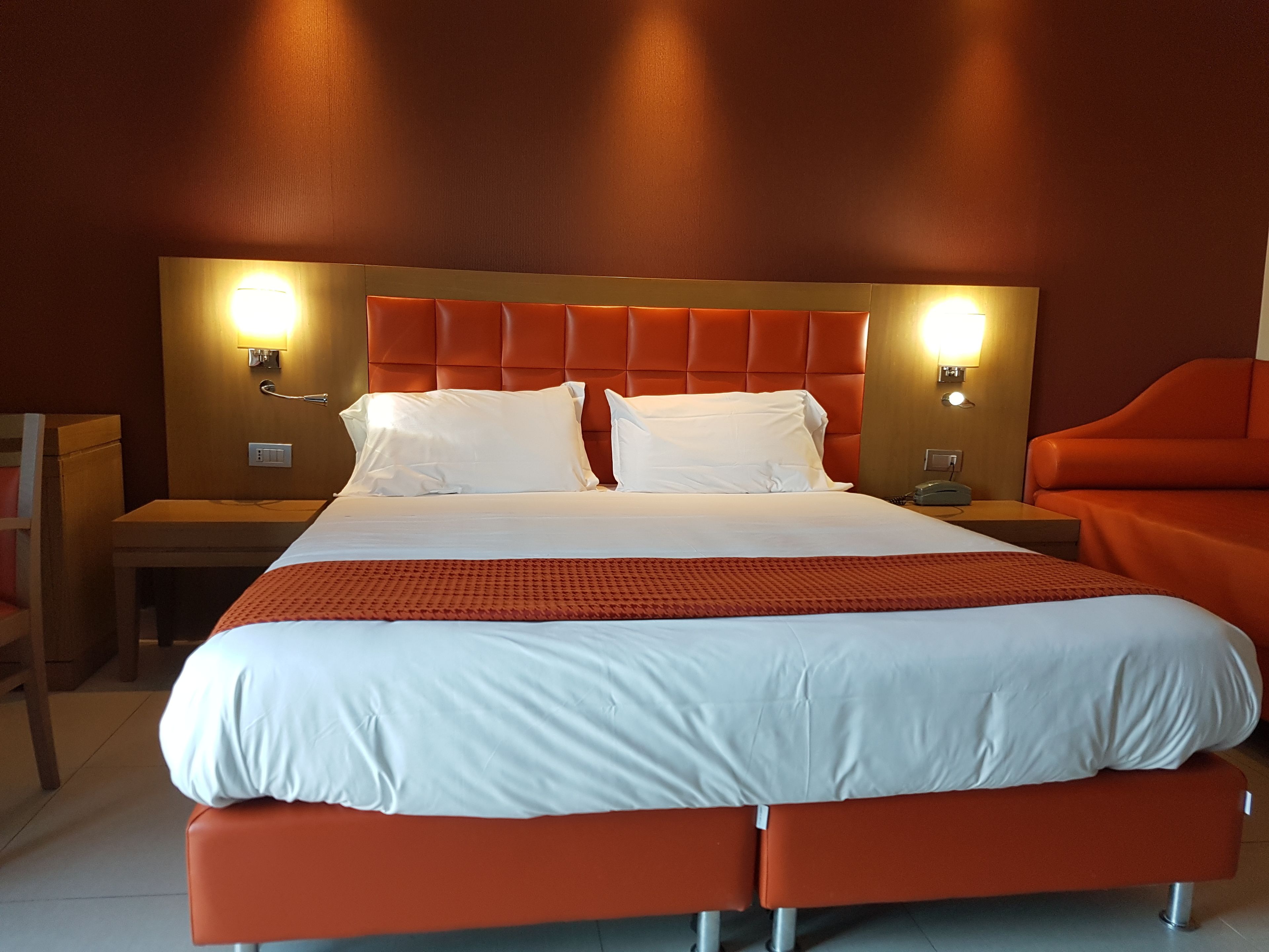 Ein Hotelzimmer mit einem großen Bett, zwei Nachttischen und einem Sessel.