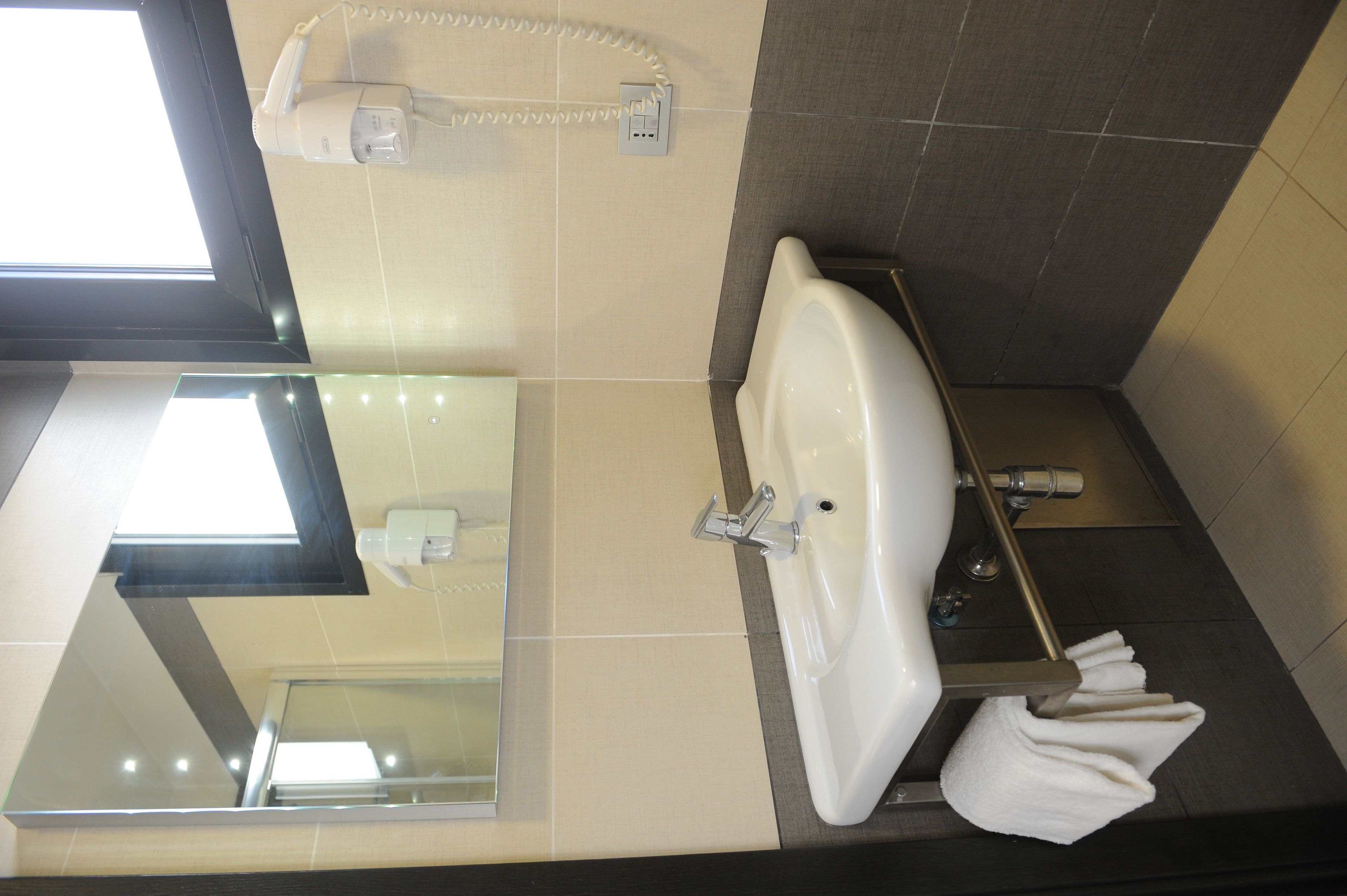 Un baño con lavamanos, espejo, toallero y teléfono.