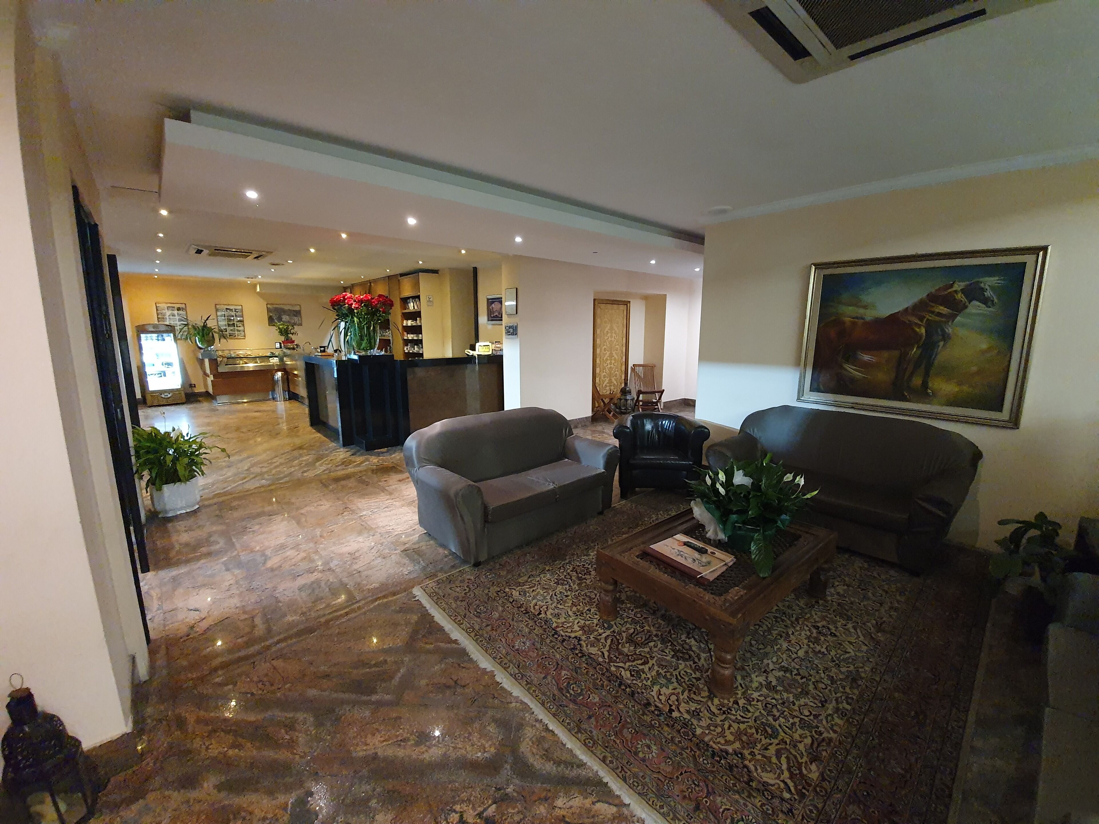 Un hall con mostrador de recepción, zona de estar y un cuadro en la pared.