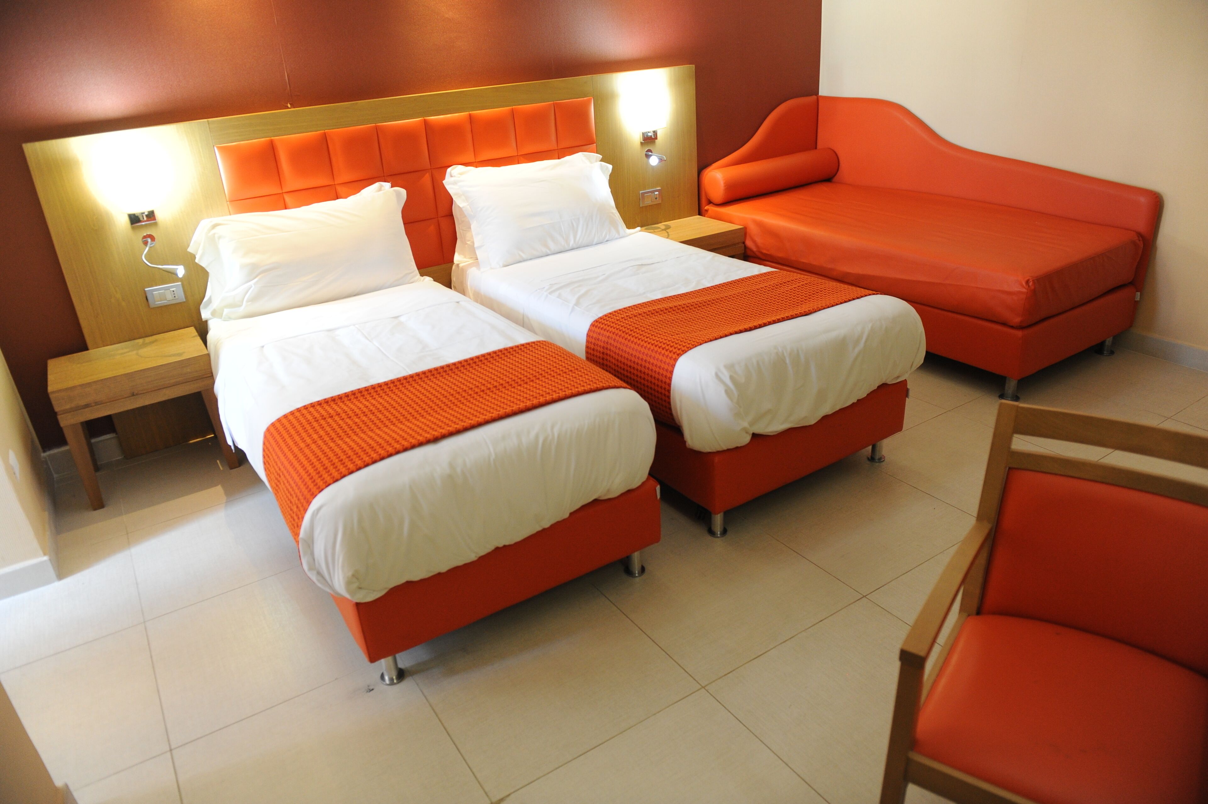 Una habitación de hotel con dos camas, un sofá y una silla.