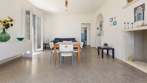 Uma sala de estar moderna com área de jantar, lareira e um corredor que dá para outro cômodo.