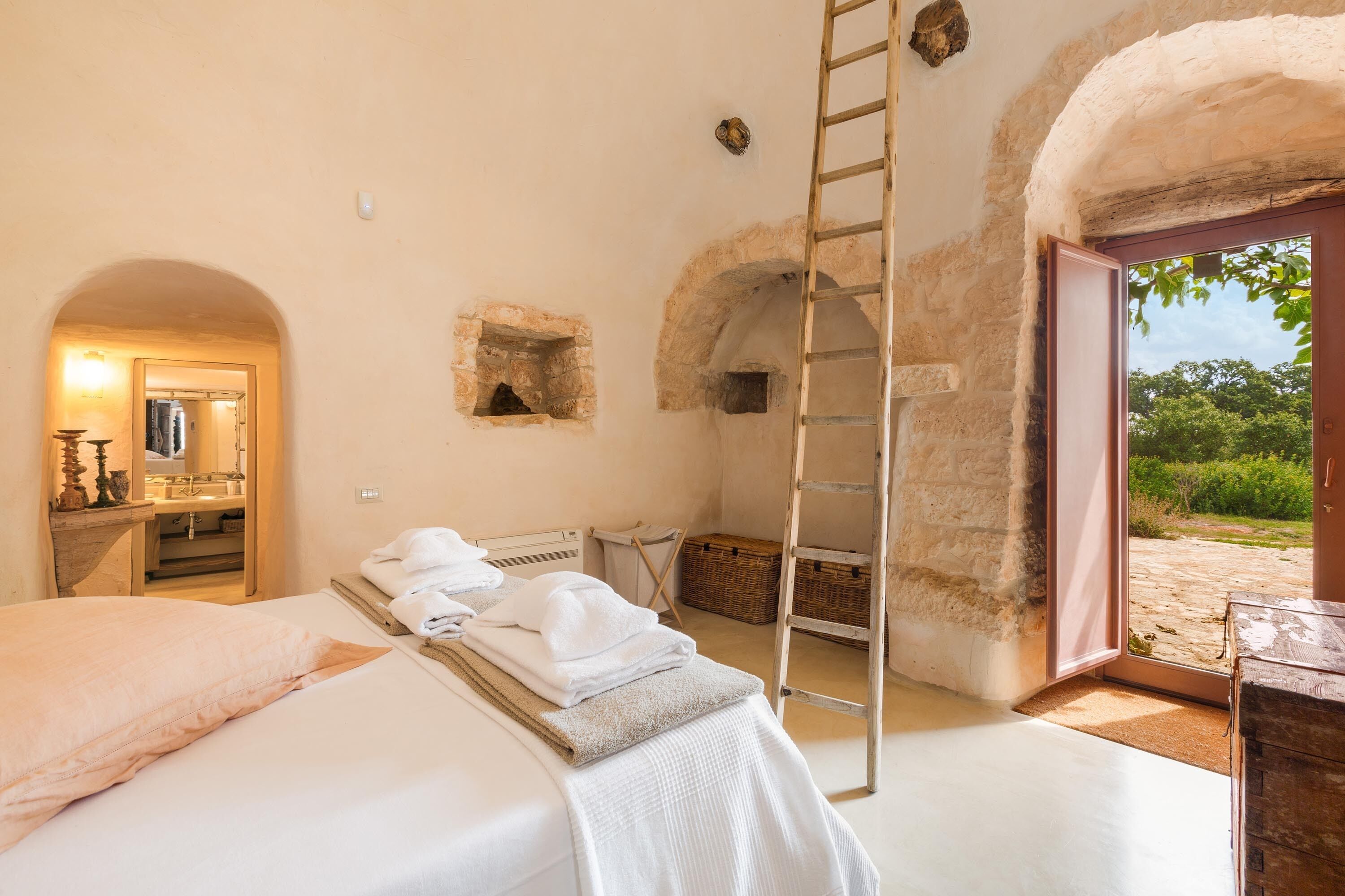 Une chambre avec un lit, une échelle et une vue sur l’extérieur.
