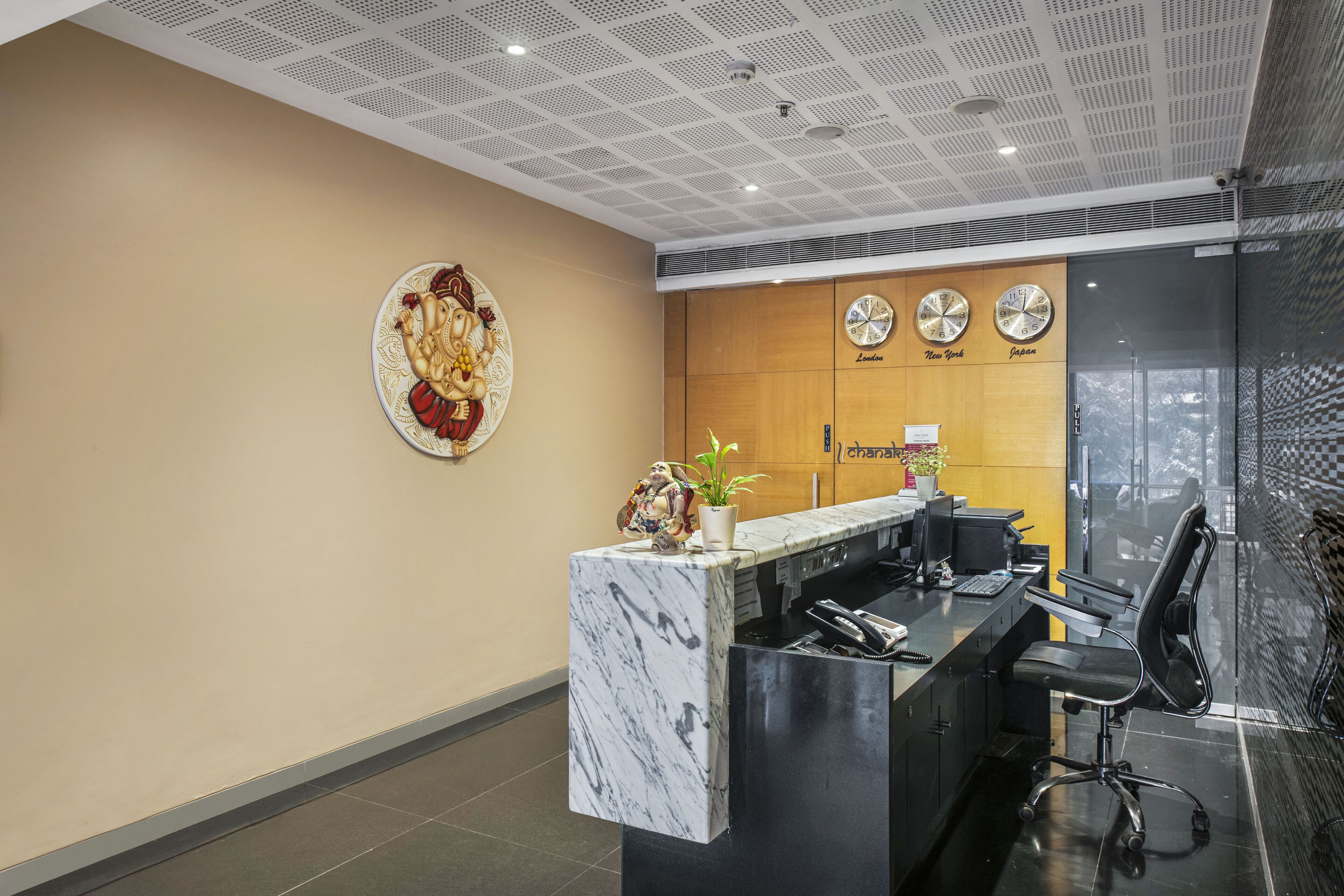 A reception desk with a marble top, a clock, and a decorative plate on the wall.
