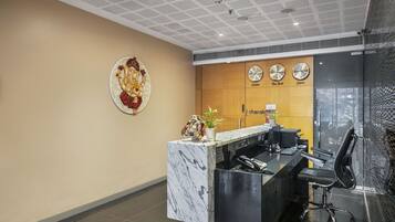 A reception desk with a marble top, a clock, and a decorative plate on the wall.