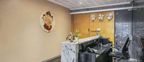 A reception desk with a marble top, a clock, and a decorative plate on the wall.