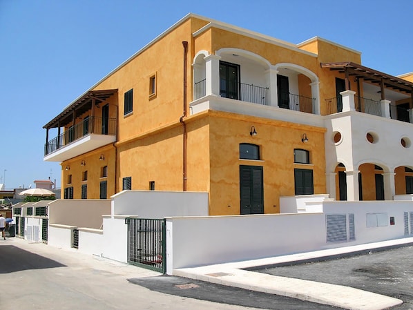 Un immeuble de deux étages avec une façade jaune, des ornements blancs et de nombreux balcons.
