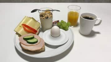 A breakfast plate with ham, cheese, cucumber, egg, and a glass of orange juice.