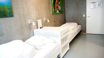 Habitación de hotel con dos camas, un cuadro en la pared y una puerta con un cartel.