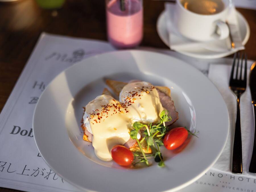 Une assiette de nourriture comprenant des œufs pochés, des légumes verts et des tomates cerises.