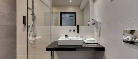 A modern bathroom with a glass-enclosed shower, a black sink, and a mirror.