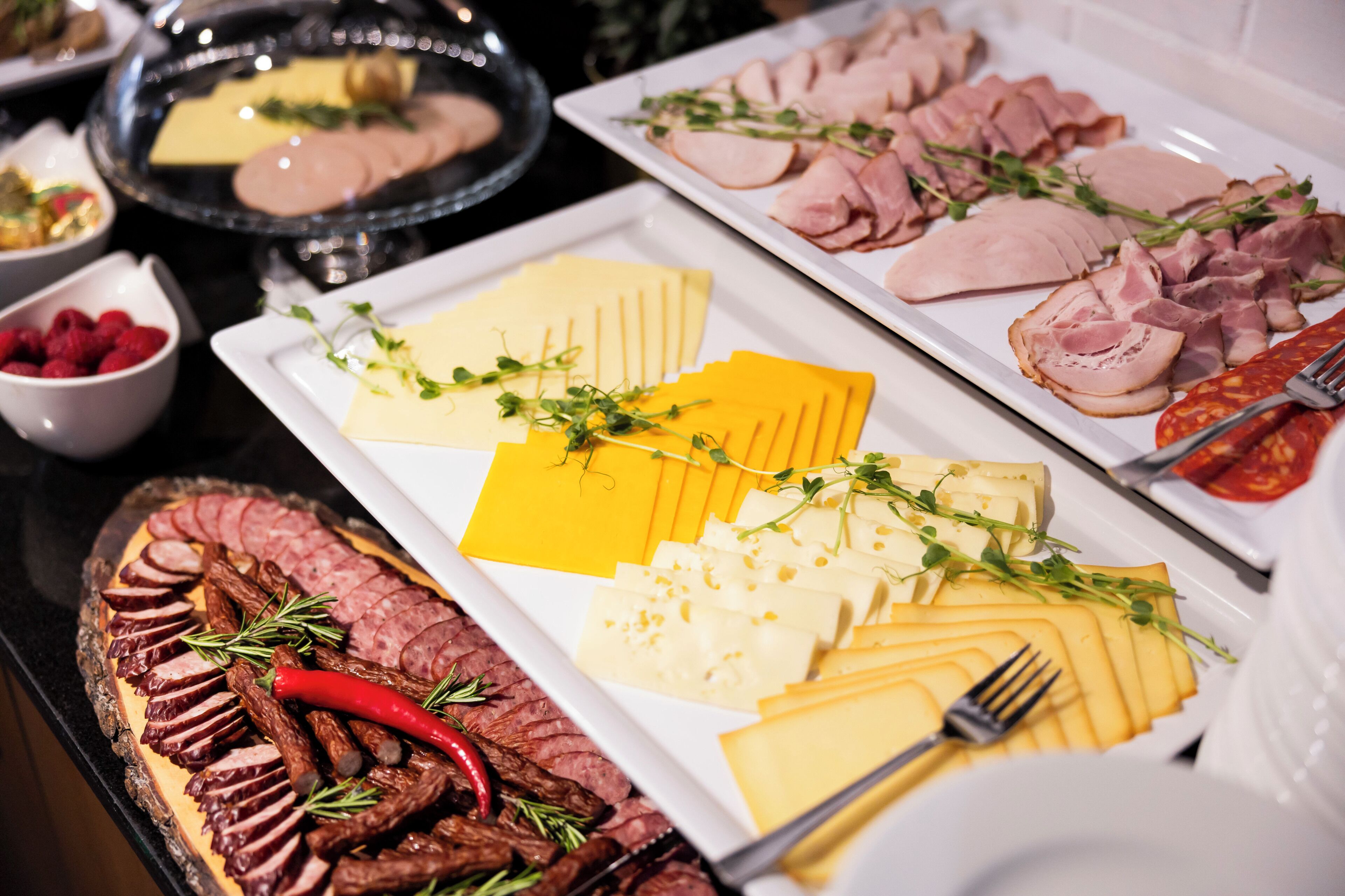 A buffet with various food items including sliced meats, cheeses, and garnishes.