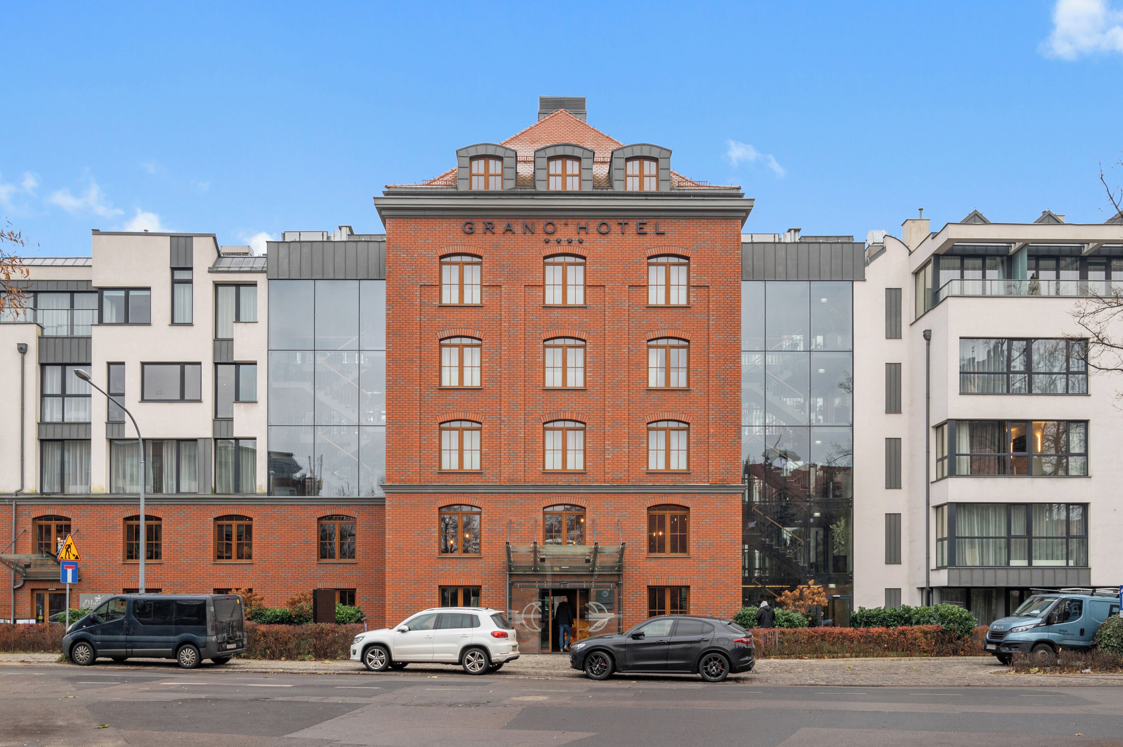 Ein Backsteinhaus mit der Aufschrift 'GRANO HOTEL' an der Fassade, mit mehreren Fenstern und einem modernen Design.