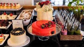 A buffet with various desserts including cakes and fruit tarts.