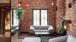 A modern interior with brick walls, large windows, and a seating area with a sofa and a table. - Grano Hotel**** Gdańsk Riverside (Gdansk)
