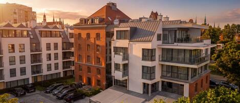 A multi-story residential building with a parking area and a covered outdoor seating area.