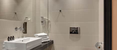 A modern bathroom with a white sink, mirror, and toilet.