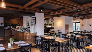 Un interior de restaurante con vigas de madera, suelo a cuadros blanco y negro, y varias mesas y sillas.