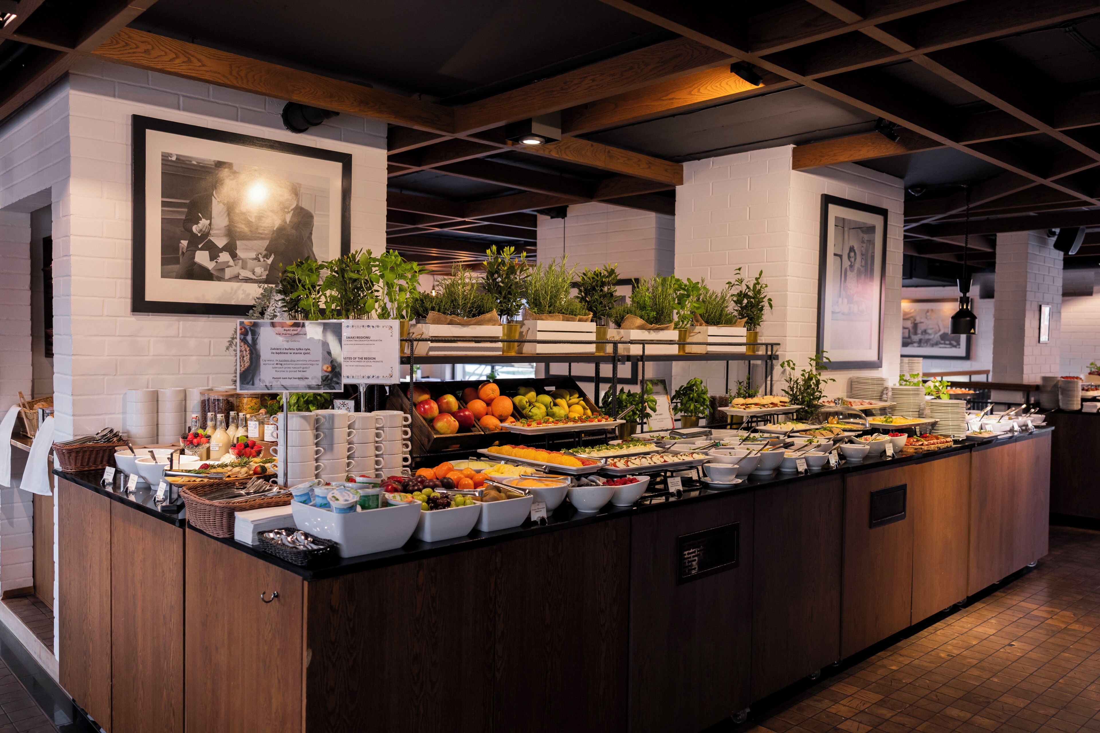 Un buffet proposant une variété de plats, des poutres en bois au plafond et des tableaux encadrés aux murs.