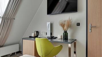 Ett modernt hotellrum med ett skrivbord, en stol, en platt-TV och ett element.