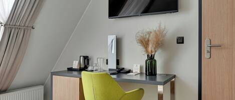 A modern hotel room with a desk, chair, flat-screen TV, and a radiator.